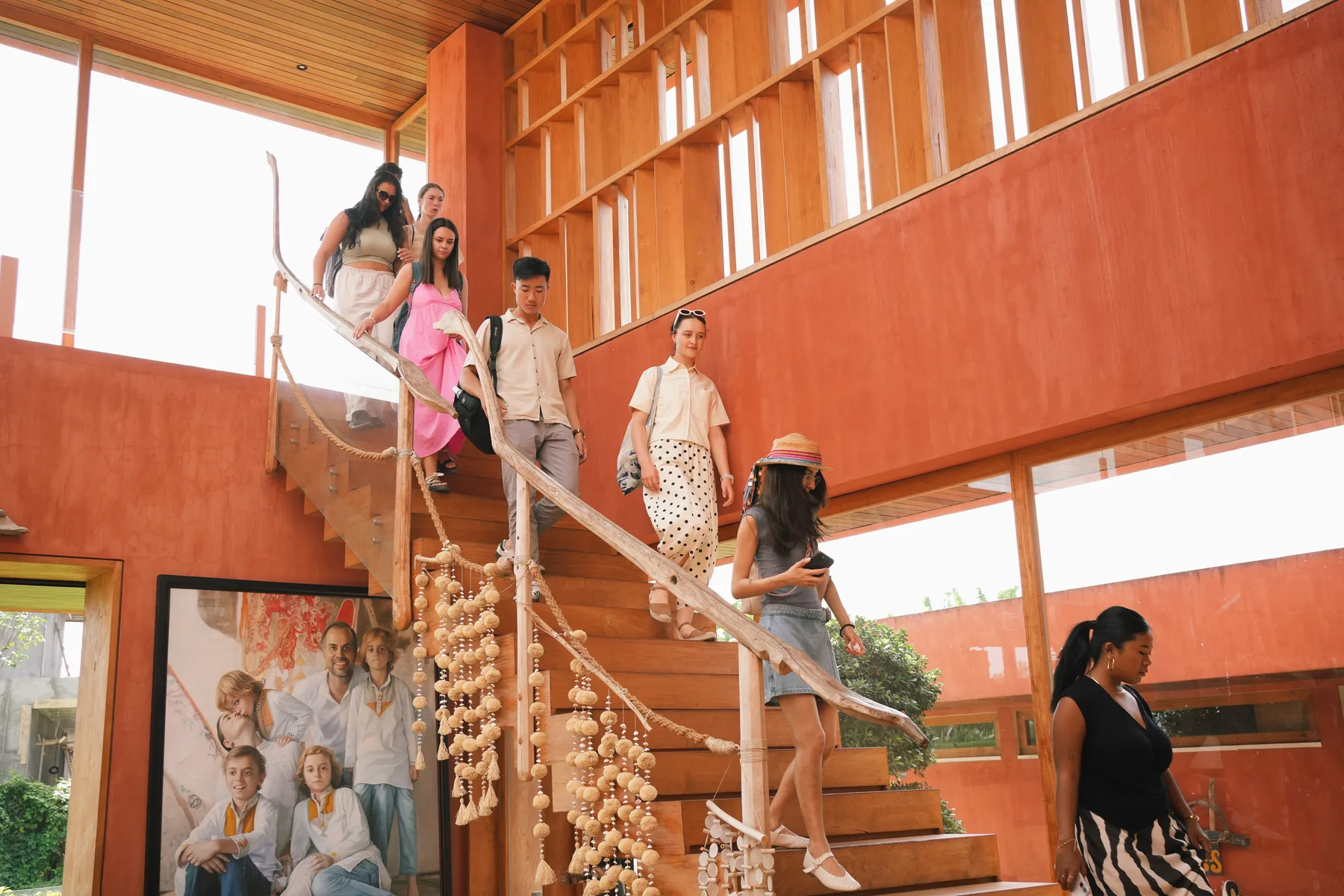 Students descending a sculptural wooden staircase with a tree-branch handrail at Nenek Coco Villa