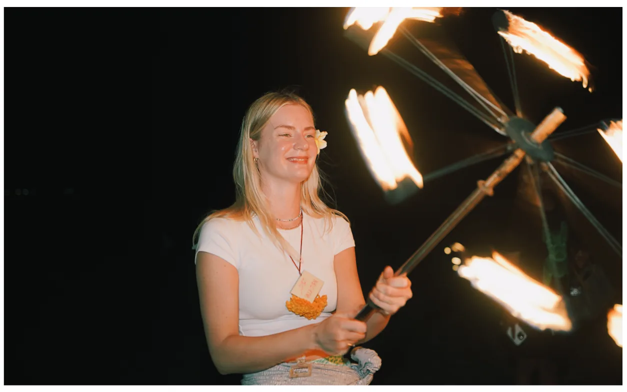 A student spinning a fire fan with several flames during the fire show